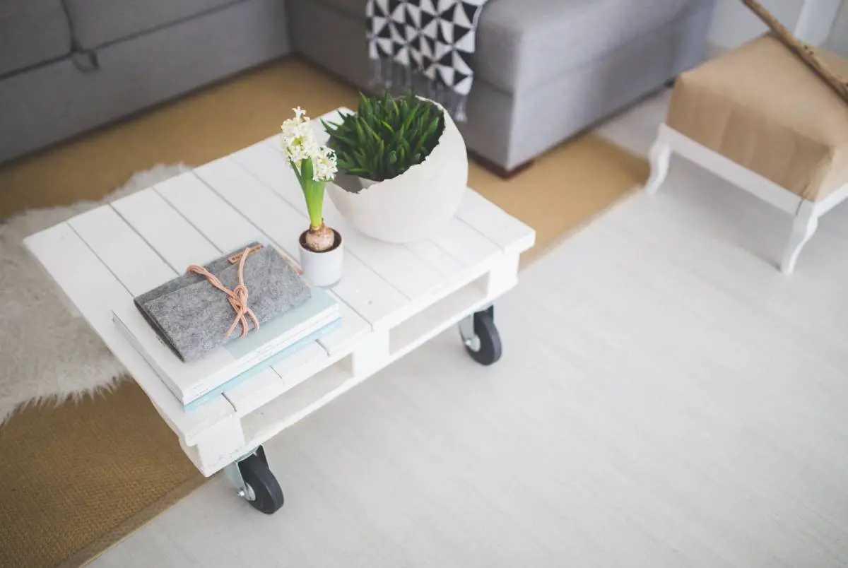 A white table with books and plants on top of it.