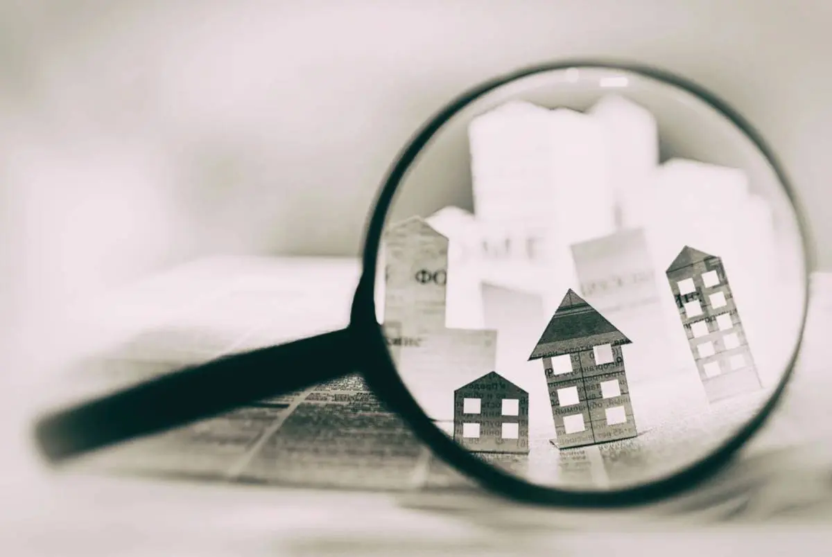 A magnifying glass over some paper houses